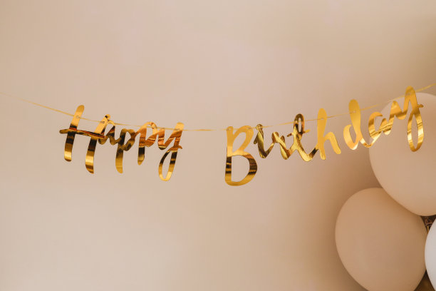 “生日快乐”的金色气球文字排列在墙上装饰派对活动。对象和背景照片图片下载