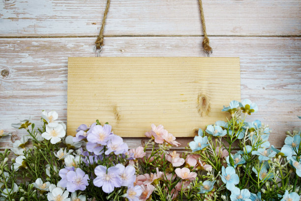 用绳子悬挂的木牌和木制背景上的人造花装饰的空白空间图片下载