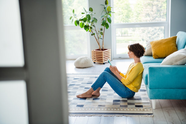 千禧一代博主女士的侧面照片，坐在地板沙发上使用现代科技在公寓里聊天图片下载