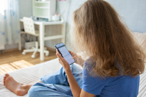 一个可爱的少女正在用智能手机看视频或写信息图片下载