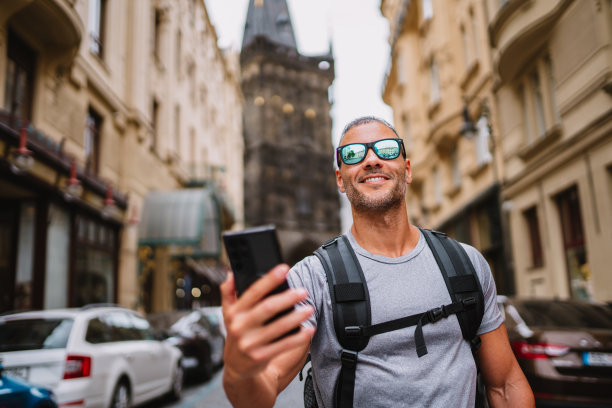 年轻人背着背包，用智能手机拍街头照片。图片下载