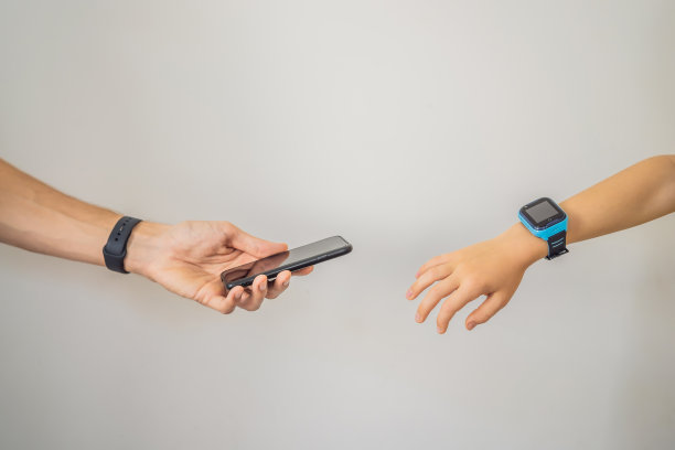 爸爸的手伸向智能儿童手表里孩子的手。爸爸表示他的孩子受到保护。智能手表，婴儿安全。孩子上课，听音乐，给朋友打电话图片下载
