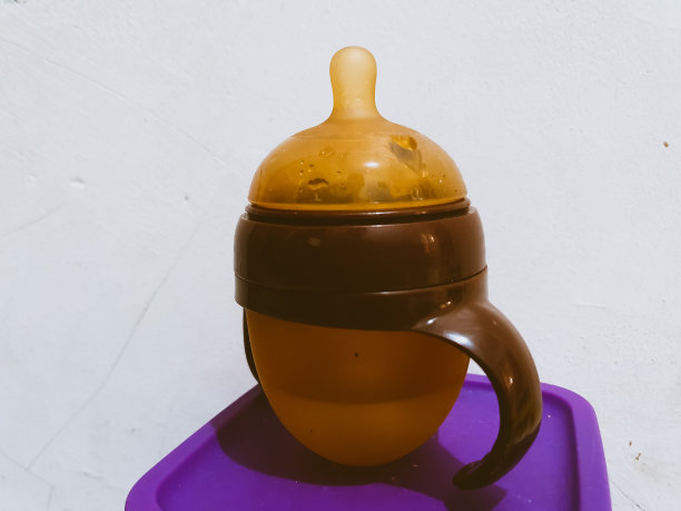 棕色的婴儿奶瓶。带把手的婴儿奶嘴。图片下载