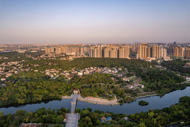 傍晚河边的城市建筑和森林鸟瞰图图片下载