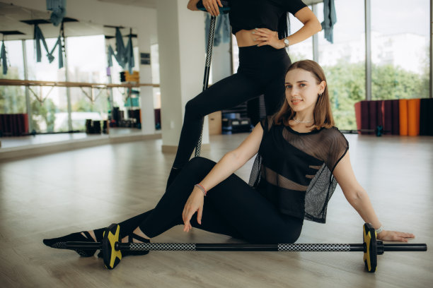 室内肖像的快乐年轻健康的女人在健身房摆姿势，拿着杠铃，健康的生活方式的照片图片下载