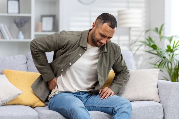 坐在沙发上背部疼痛的非裔美国青年图片下载