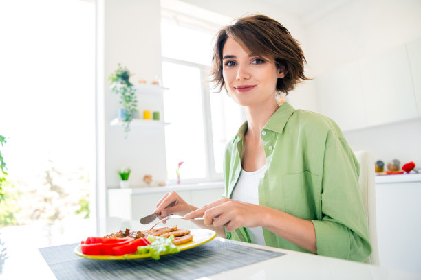 照片宁静可爱的女孩坐在椅子厨房桌子拿刀叉吃美味的自制午餐盘明亮的室内平坦图片下载