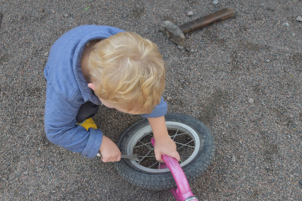 一个小男孩用扳手修理自行车轮子，照片中没有滤镜图片下载