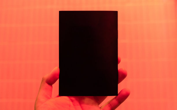 手拿着一本空白封面的书，上面有红蓝色的霓虹灯。图片下载