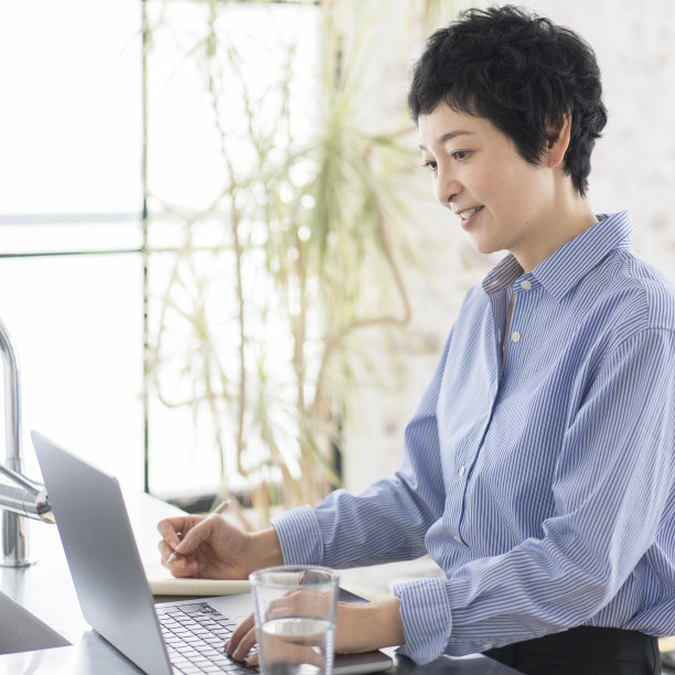 一个女人正站着用笔记本电脑工作。图片下载