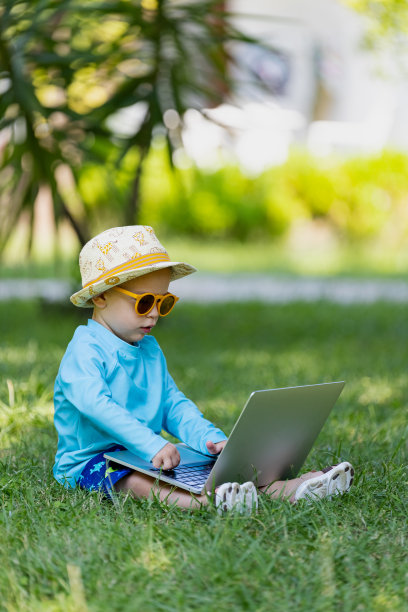 小男孩双手放在电脑键盘上，看着笔记本电脑屏幕。孩子和科技度假的概念。图片下载