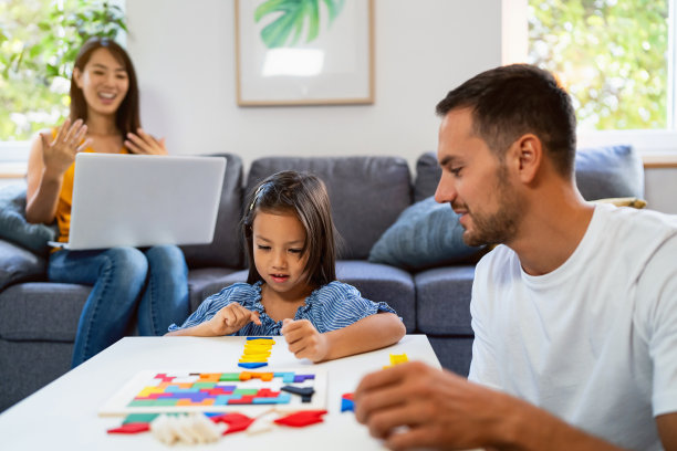 母亲在家用笔记本电脑工作，而她的丈夫和女儿在玩拼图图片下载