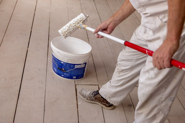 一个人在空房间里用油漆滚筒刷白墙图片下载