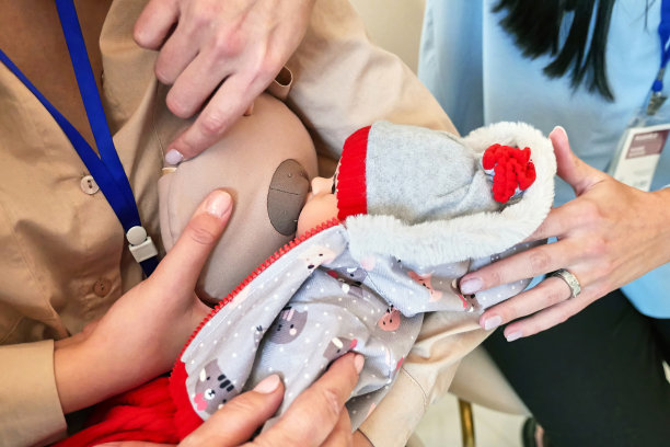 这张照片不是一个“活”的孩子，而只是一个孩子的娃娃(假人)。一位年轻的准妈妈在婴儿和乳房模型上学习母乳喂养。为做母亲做准备。图片下载