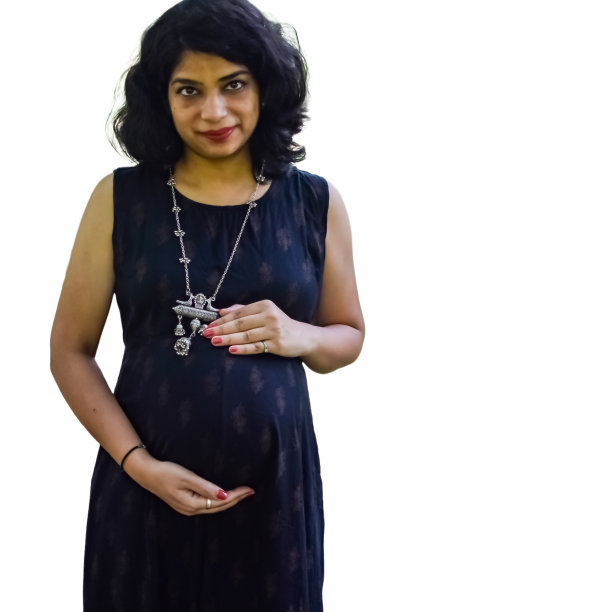 一名怀孕的印度妇女摆姿势拍摄怀孕照片，双手放在腹部，背景是白色的，印度孕妇穿着朴素的孕妇装，把手放在肚子上，拍摄怀孕照片图片下载