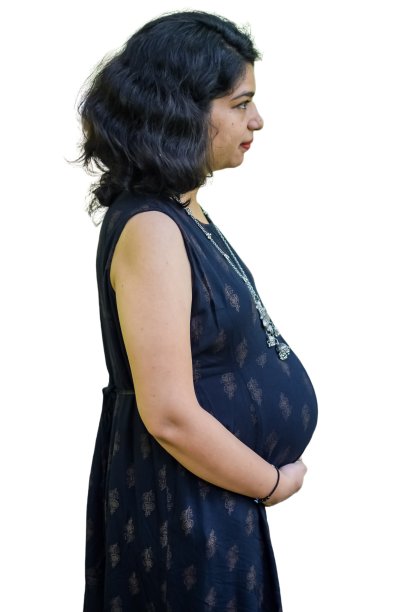 一名怀孕的印度妇女摆姿势拍摄怀孕照片，双手放在腹部，背景是白色的，印度孕妇穿着朴素的孕妇装，把手放在肚子上，拍摄怀孕照片图片下载