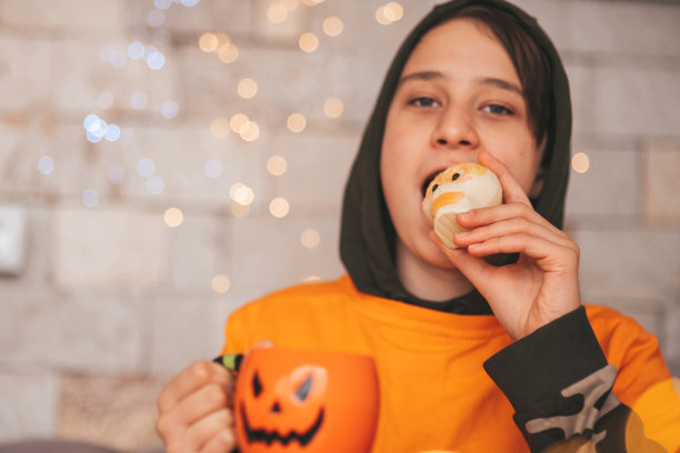 真实的变焦男孩在万圣节派对上与杰克灯笼杯子和糖果合影图片下载