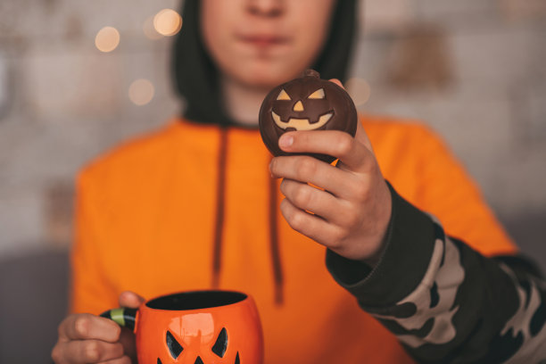 真实的变焦男孩在万圣节派对上与杰克灯笼杯子和糖果合影图片下载