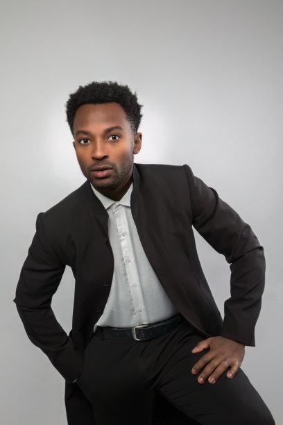 商人穿着黑白相间的孤立肖像，20多岁的成功男子手放在大腿上图片下载