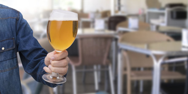 在酒吧或酒馆里，手拿一杯啤酒图片下载