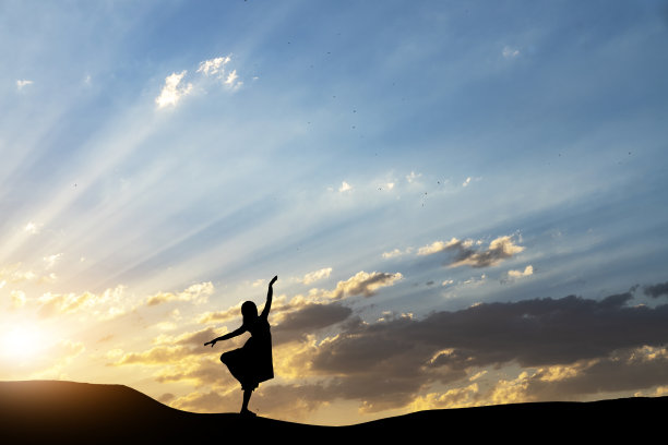 女人的剪影在夜晚跳舞，在明亮的夕阳背景下。图片下载