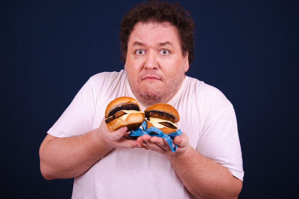 有趣的饥饿胖子吃汉堡。图片下载