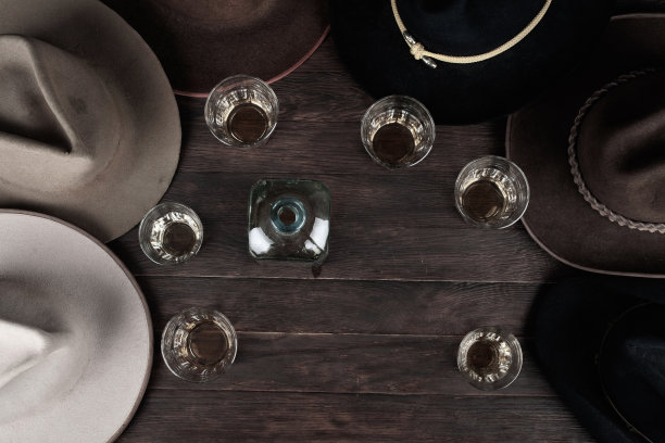 波旁威士忌，桌上放着古老的西部帽子。前视图。图片下载