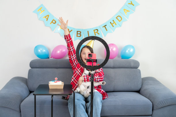 一个十几岁的女孩和她有趣的宠物狗正在庆祝她的生日，并在家里为他们的Tiktok视频博客拍摄视频。Z世代达人玩视频自拍拍秀app分享病毒故事。图片下载