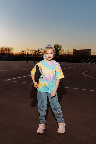 穿着休闲服和牛仔裤的时尚小女孩站在滑板旁图片下载