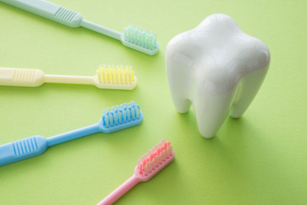 白色的牙齿和绿色背景的彩色牙刷。图片下载