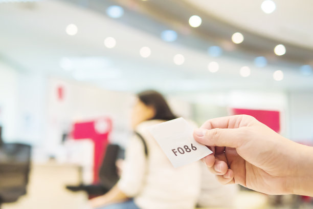 在现代化的接待区，一名男子手持排队卡等候图片下载