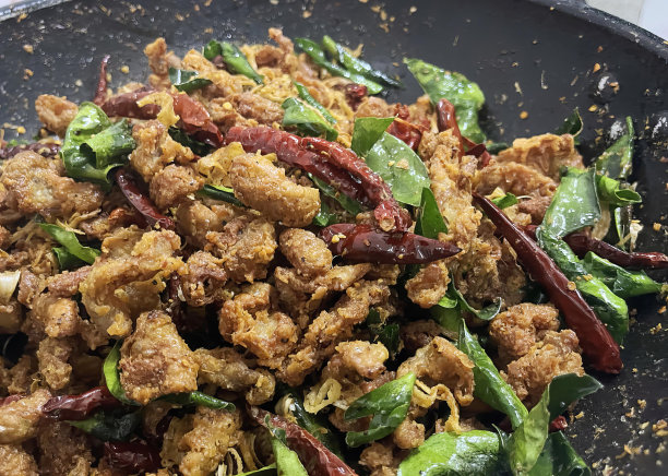 一张照片上的锅里盛满了混合的食物，还有一个黑色的盘子里放着翻炒的食物。图片下载