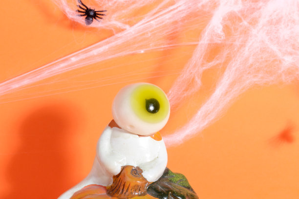 一只眼睛幽灵接近蜘蛛蛛网般的橙色背景图片下载