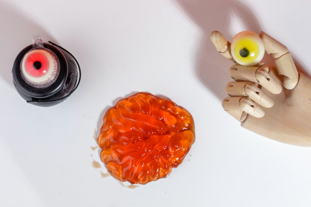 万圣节的概念与人体模型手拿糖果的眼睛，软糖的大脑和眼睛女巫锅在白色的背景图片下载