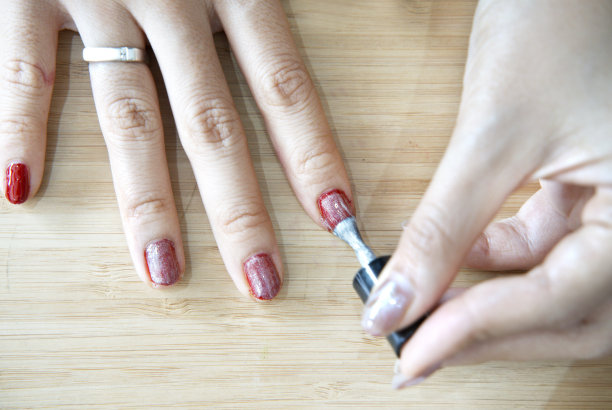 一个女人做美甲的特写镜头，指甲涂成红色图片下载