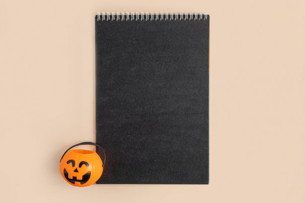 空白的黑色纸张与万圣节装饰在柔和的米色背景。贺卡，时髦的邀请模型。铭文的地方。南瓜。现代最小邀请模拟，模板。俯视图图片下载