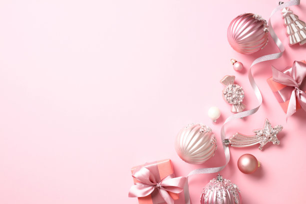 圣诞横幅设计。时尚的圣诞装饰，彩带，球，礼盒在粉红色的背景俯视图照片。图片下载