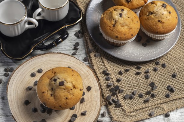 木桌背景上有巧克力屑的松饼或纸杯蛋糕。制作工业糕点或自制糕点的概念。图片下载