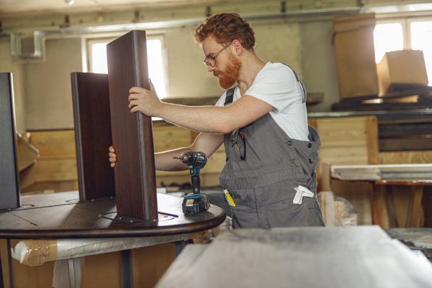 木工站在木工车间用电钻固定工作台。高质量照片图片下载