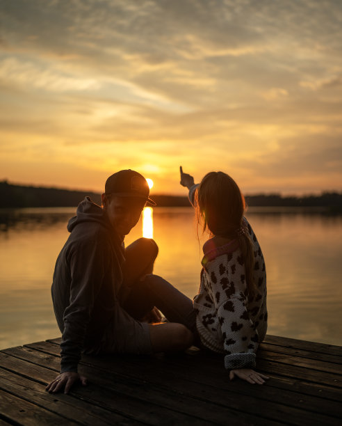 在码头上放松身心欣赏日落美景的浪漫情侣（竖版图片）图片下载