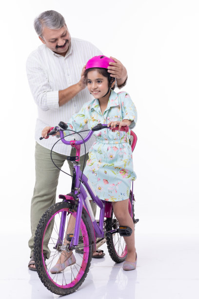 一位父亲教女儿在白色背景上骑自行车的全身像图片下载