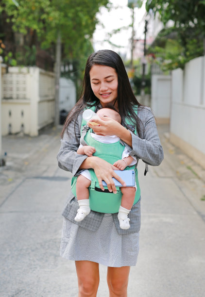 年轻的女商人抱着她的婴儿，手里拿着孩子的奶瓶。图片下载