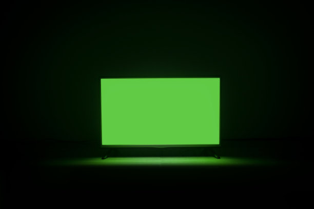 4K液晶电视切色度键绿屏在暗背景地板上。图片下载