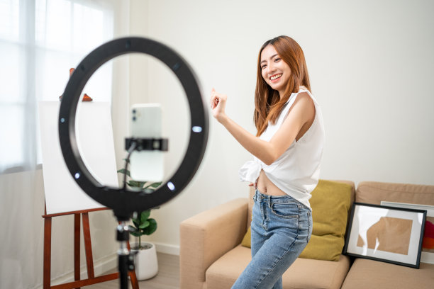 年轻的时尚影响者亚洲女人在家里的客厅里用手机跳舞。创作者，视频博主，才艺舞蹈，享受爱好，内容录制，展示视频分享在社交媒体上。图片下载