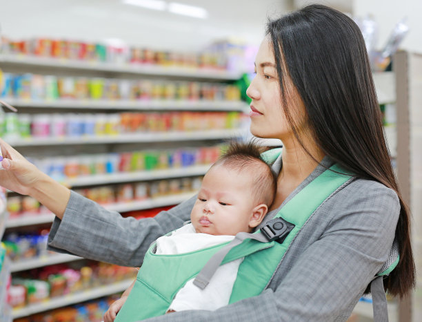 一名女商人在便利商店用臀部抱着她的男婴。图片下载