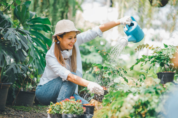 年轻女性的爱好是照顾植物，浇水，铲花。在工作休息的时候在花园里图片下载