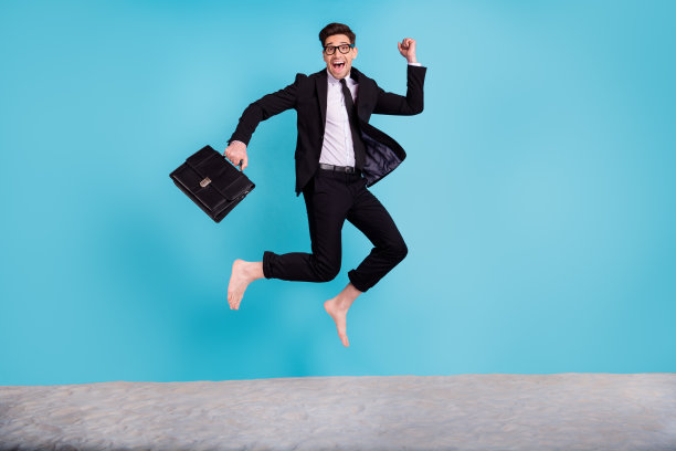 幸运的漂亮男人全身照片穿黑色西装箱跳高庆祝夏天的旅程孤立的蓝色背景图片下载