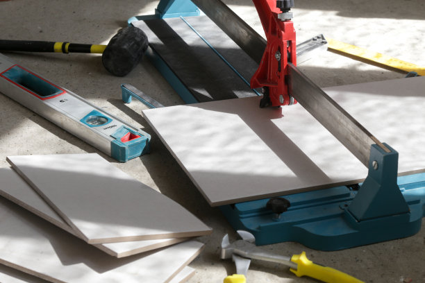 使用标准的手动瓷砖切割机切割瓷砖。瓷砖在浴室中逐步安装的过程。DIY家居装修。图片下载