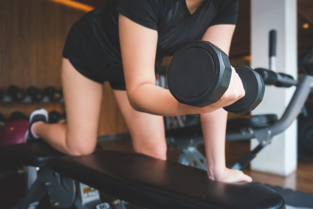 女性在健身房举哑铃的图片。健身，锻炼，健身房锻炼和健康的生活方式概念。图片下载