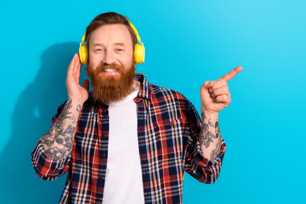 照片的大胡子红头发的男人直接手指空白空间推荐spotify耳机月最好的播放列表孤立的蓝色背景图片下载